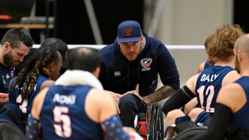 A man using a wheelchair speaks to wheelchair rugby players