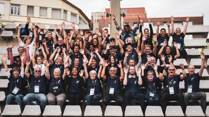 A group of people waving from a stadium stand