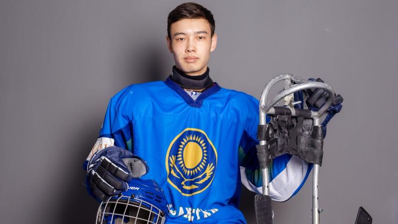 A man posing for a picture with Para ice hockey equipment