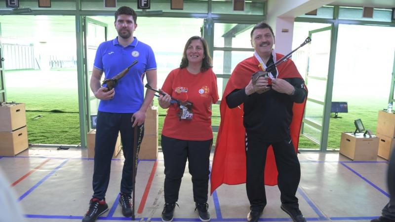 A woman standing between two men in a shooting range