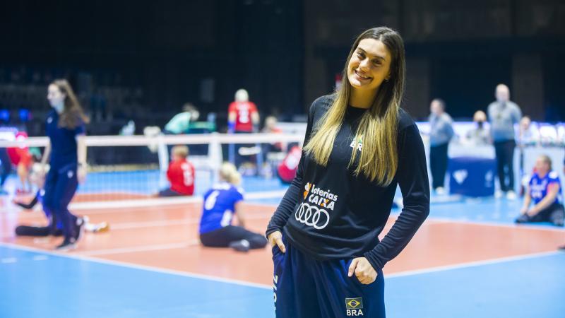 A female athlete smiling in front of a sitting volleyball court