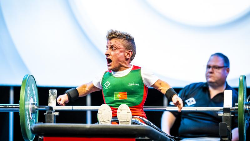 A female Para powerlifter celebrates with a cheer on the bench after a successful lift.