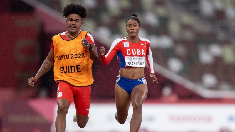 A female Para athlete runs with her male guide runner