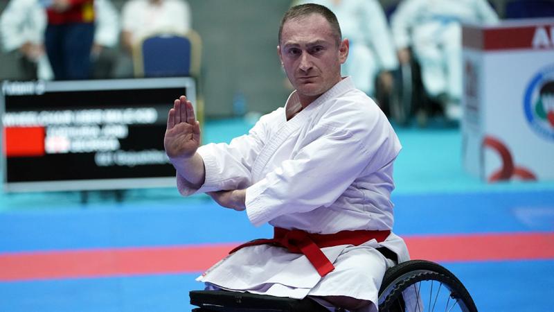 A male athlete wearing a white karate uniform performs during a competition