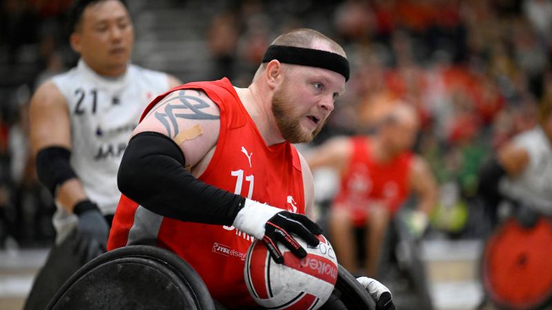 A male wheelchair rugby player carries the ball during a game