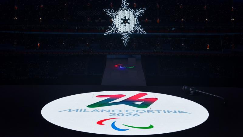 The logo of the Milano Cortina 2016 Paralympic Winter Games is projected as a bright white circle onto the stage during the handover at the Beijing 2022 Paralympic Winter Games Closing Ceremony.