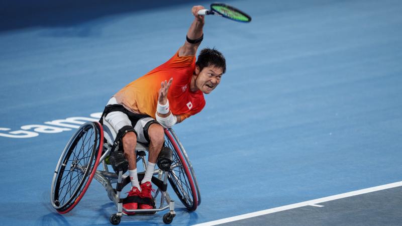 A male wheelchair tennis player holds the tennis racquet with his right hand