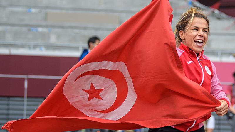 A short-stature woman celebrating with the flag of Tunisia