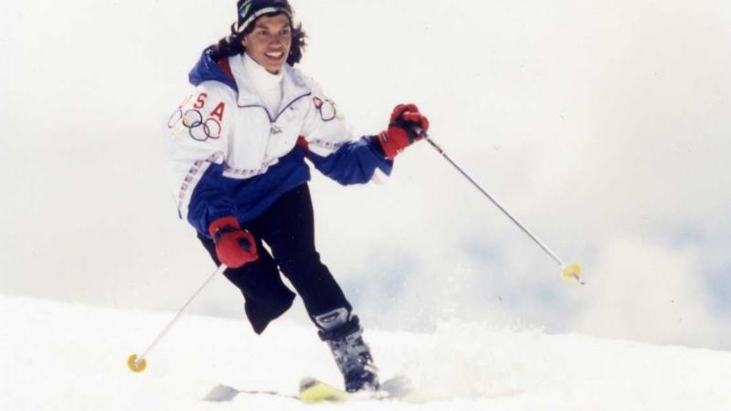 A female Alpine skier wearing a Team USA jacket skis