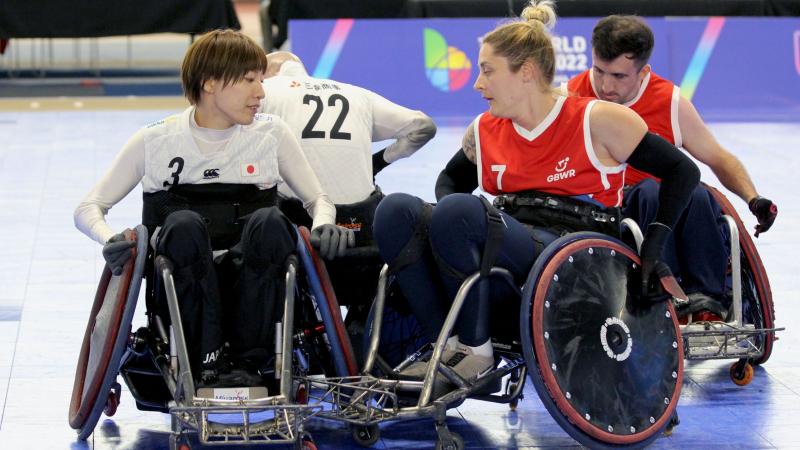 Two female wheelchair rugby players compete.