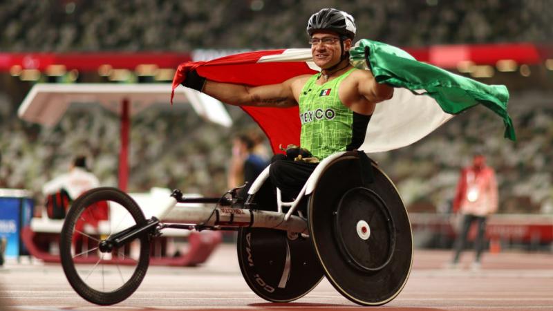 A male wheelchair racer with the Mexican flag at an athletics track