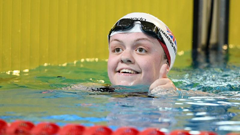 A female swimmer smiling from inside the pool