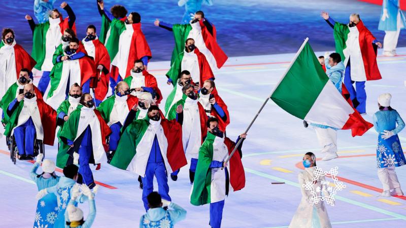 A group of about 15 athletes dressed in Italy's uniform march into the Opening Ceremony of the Beijing 2022 Paralympic Games.