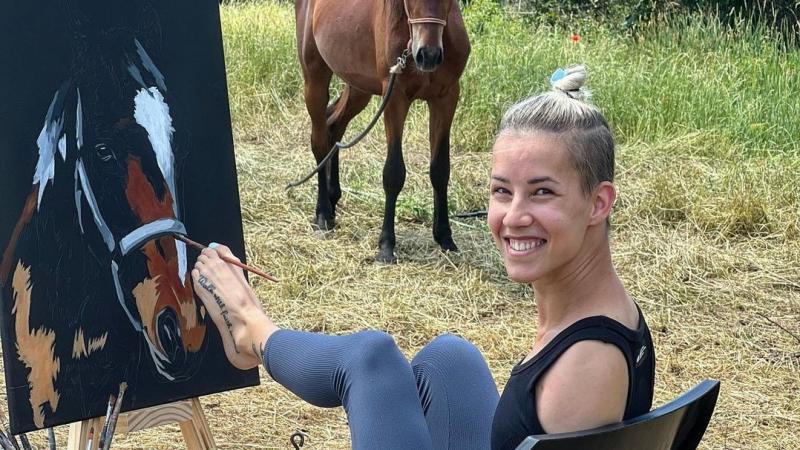 A female paints a picture of a horse with her left foot. 