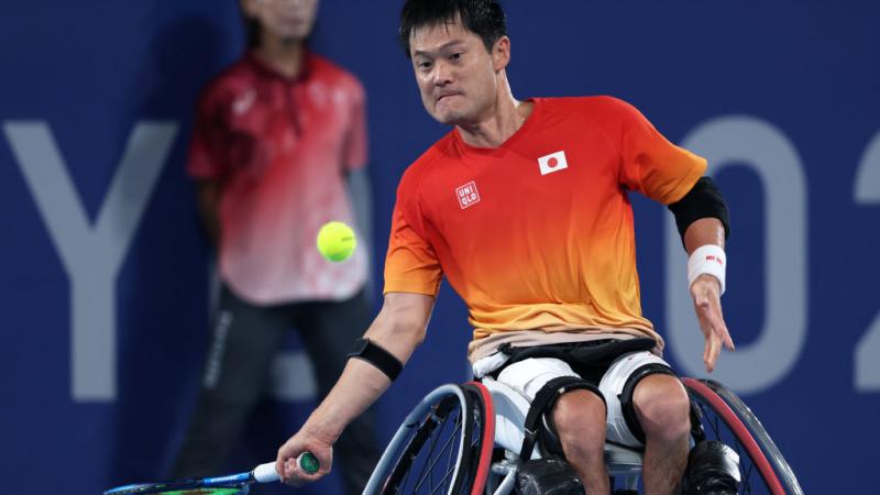 A male wheelchair tennis player prepares to hit a ball.