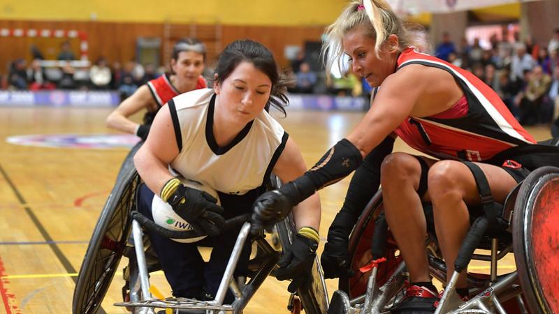 Two female wheelchair rugby players compete