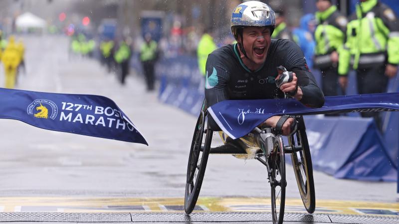 A male wheelchair racer crossing the finish line in a street marathon