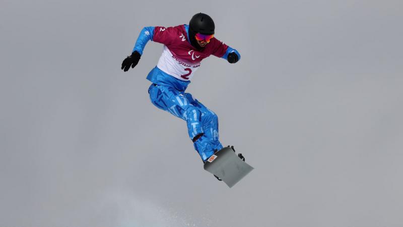 A male snowboarder jumps during his race.