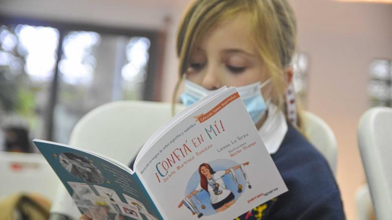 A young girl reads a children's book with a Para athlete on the cover.