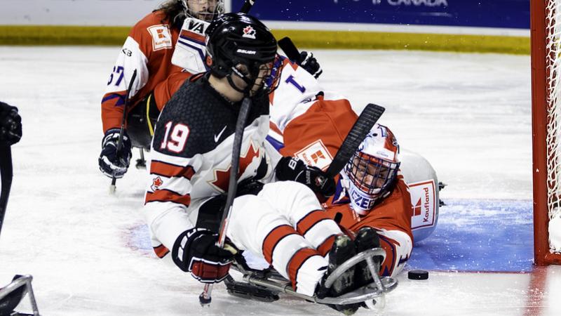 A Para ice hockey player trying to score in front of the goaltender