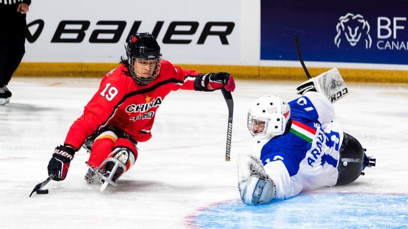 A  Para ice hockey player taking a shot in front of a goaltender