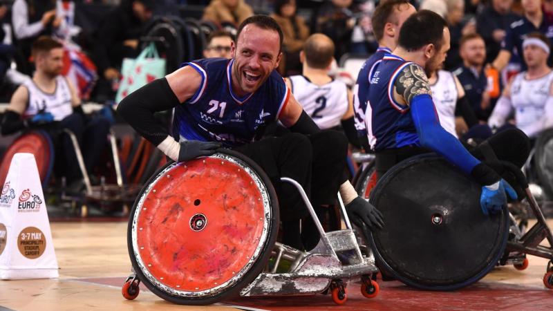 A male wheelchair rugby player smiles on the court.