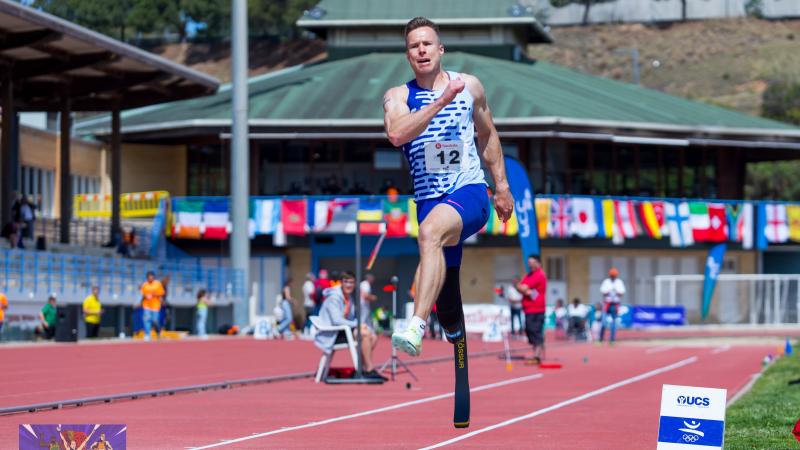 A male long jumper jumping with a prosthetic right leg