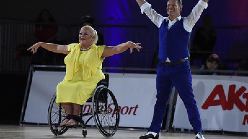 A female wheelchair dancer next to her standing male dance partner