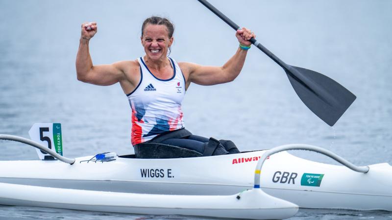 A female Para canoe athlete celebrates on her boat after winning her race at Tokyo 2020.