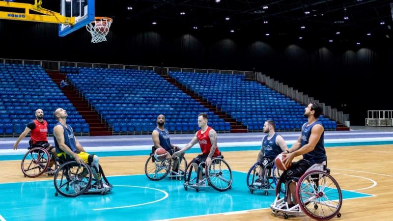 Six wheelchair basketball players train at an indoor hall.