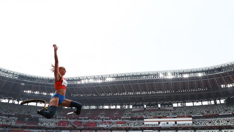 A female athlete with prosthetic legs jumping in an empty stadium