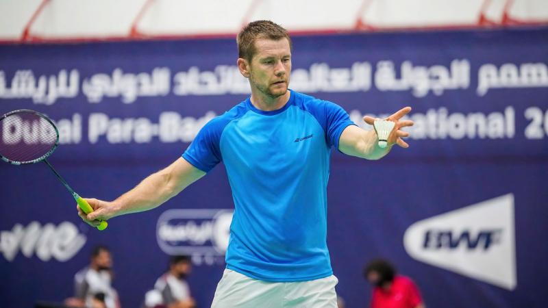 A male athlete serving in a badminton match