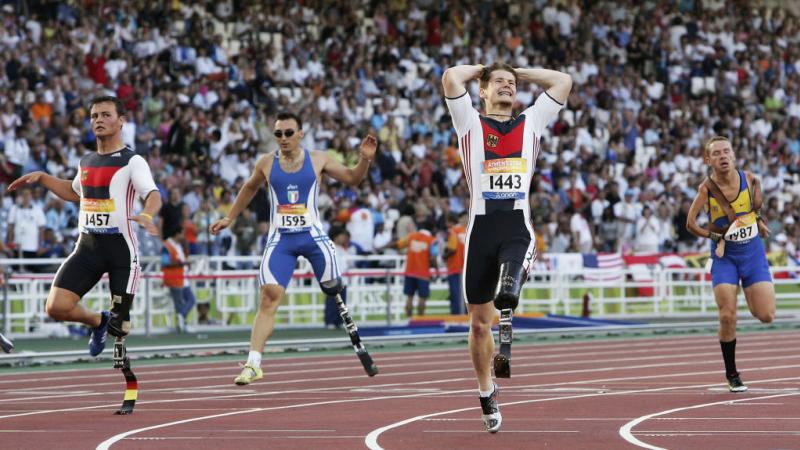 Four male athletes with blades competing on the track