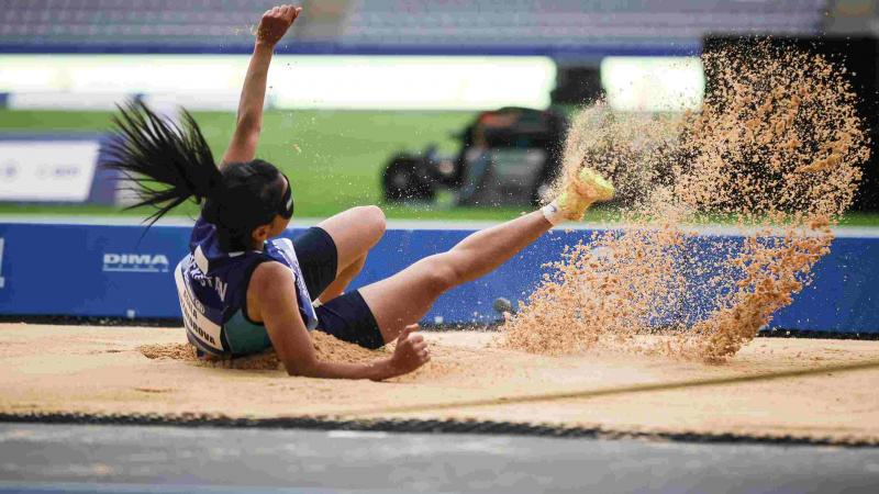 A female long jumper landing on a sand box