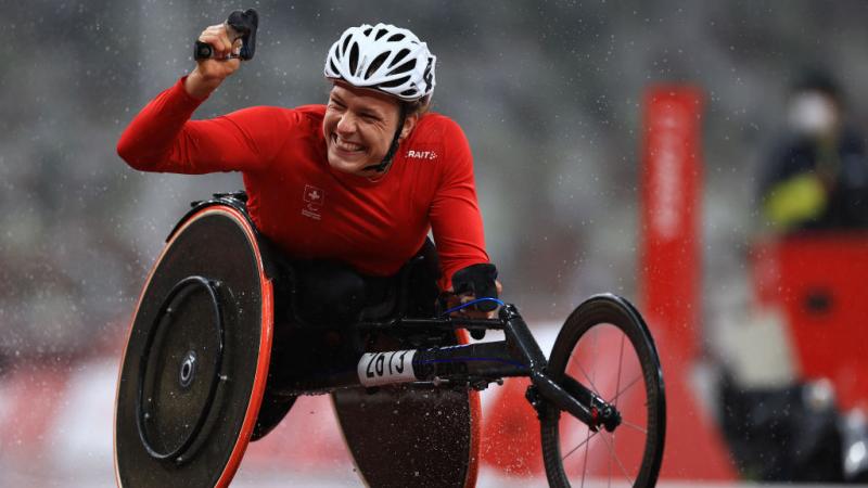 Wheelchair racer Catherine Debrunner celebrates winning with her fist raised in the air