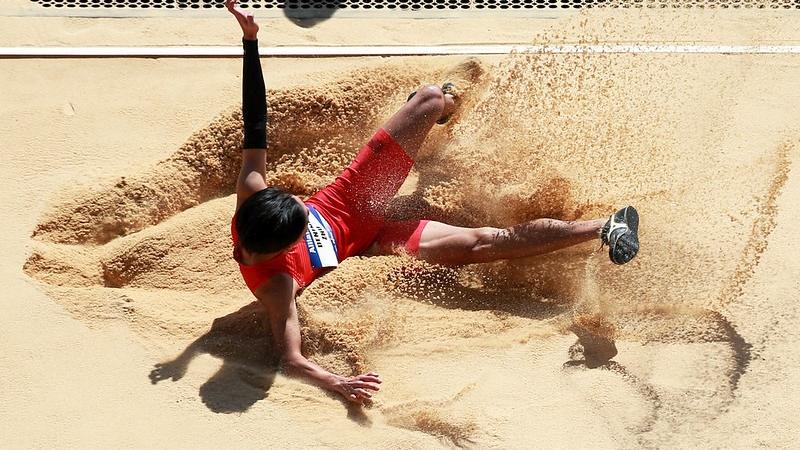 A man landing in the sand pit in a long jump event