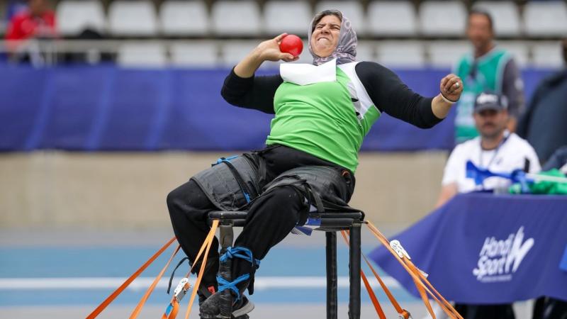 A female athlete competing in the shot put