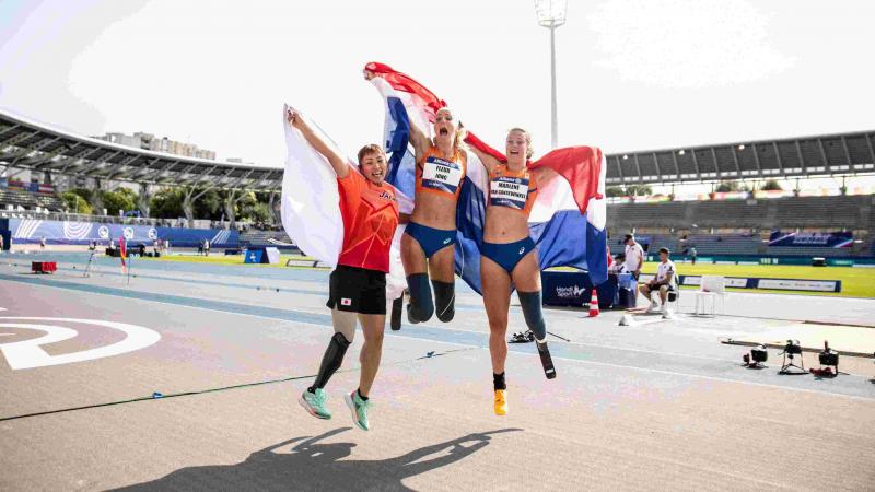 Three female athletes with prosthetic legs jumping