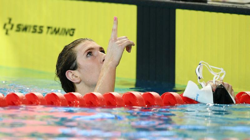 A female swimmer in the water pointing to the sky 