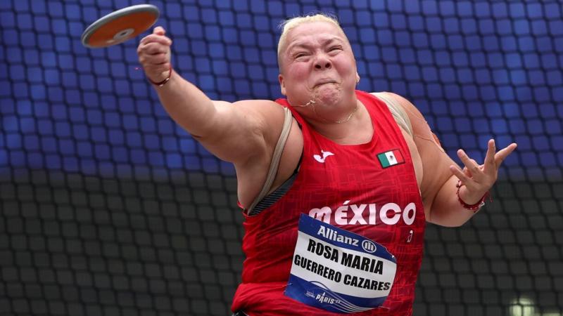 A female seated athlete throws a discus 