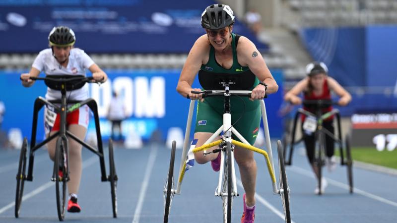 Three female athletes running with a frame on the track