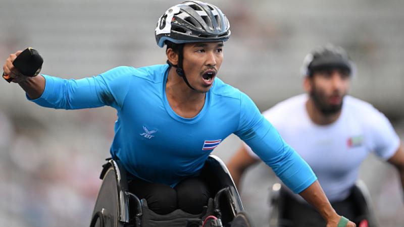 A man in a racing wheelchair celebrating 