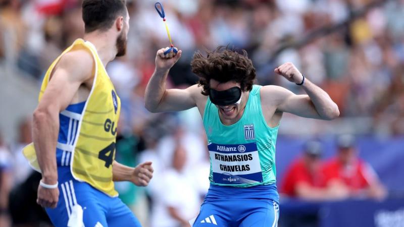 A blindfolded athlete celebrating near an athlete with a guide bib
