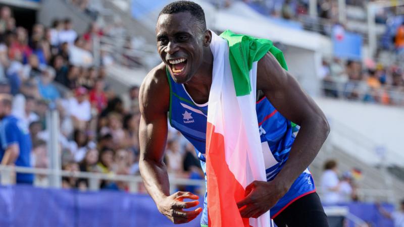 A man in athletics outfit celebrating with the Italian flag
