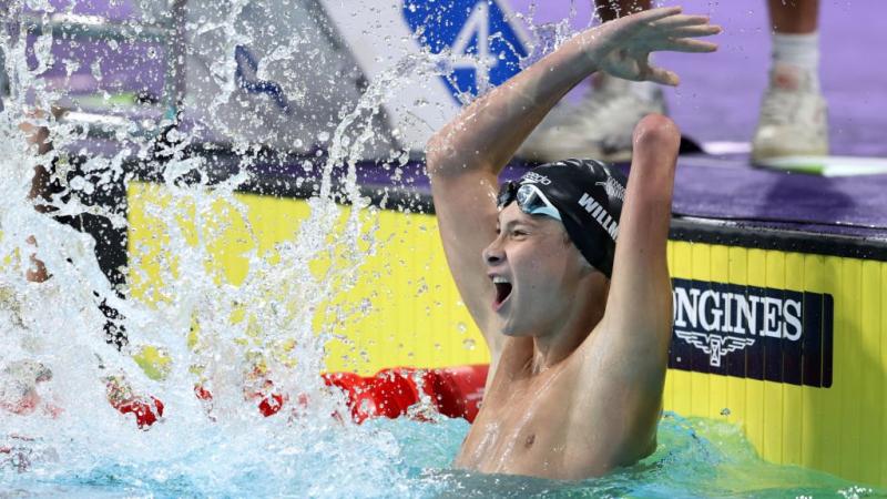 A young armless male swimmer celebrating in the pool