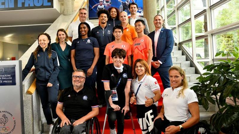 Fifteen athletes and officials pose for a photograph 