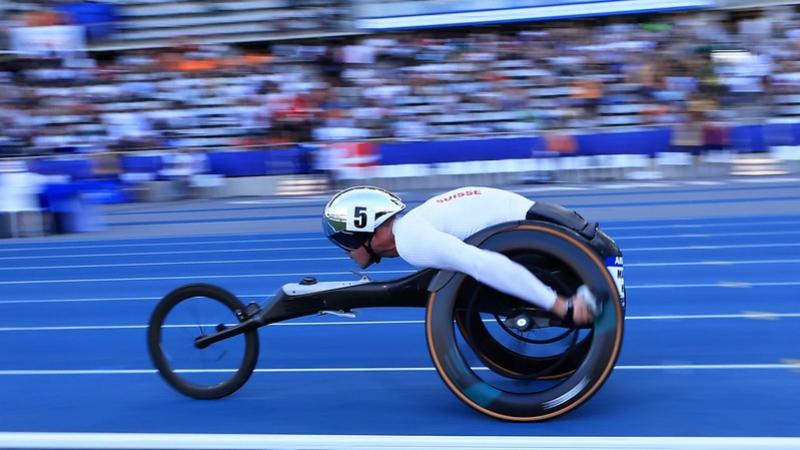 A male wheelchair racer running in front of the crowd