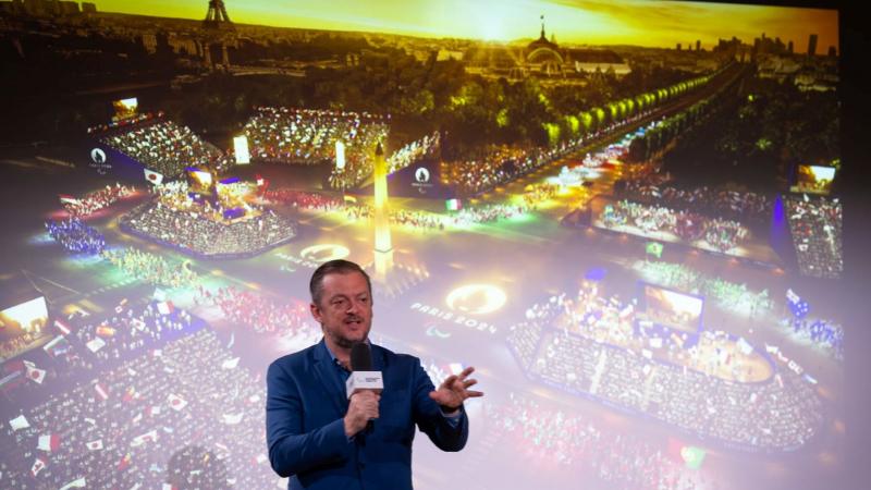 IPC President Andrew Parsons speak in front of a screen showing the Opening Ceremony of the Paris 2024 Paralympic Games