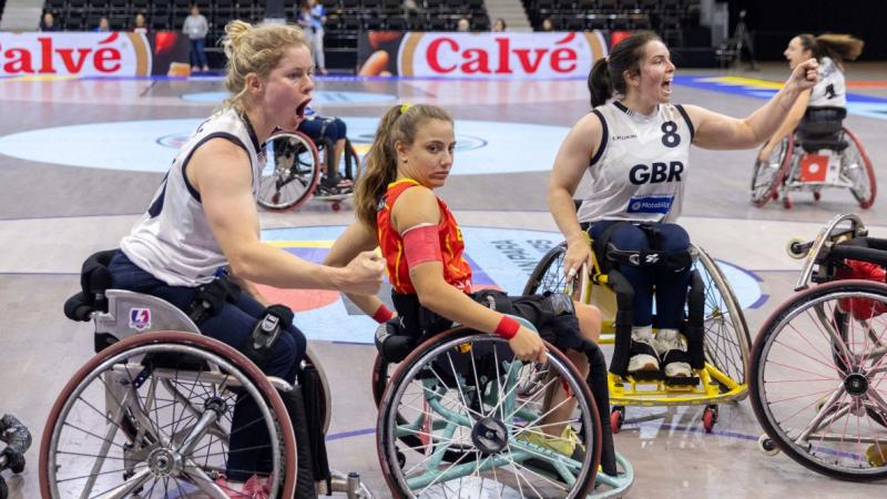 Three female wheelchair basketball players on court.