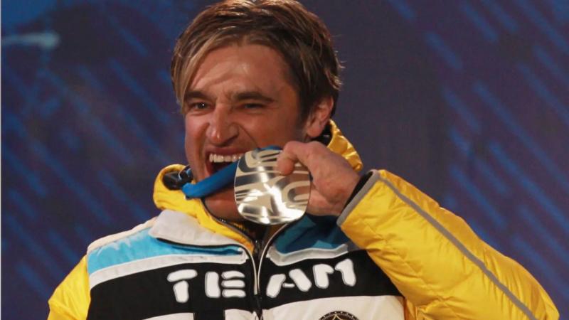 A picture of a man beating his silver medal during a medal ceremony